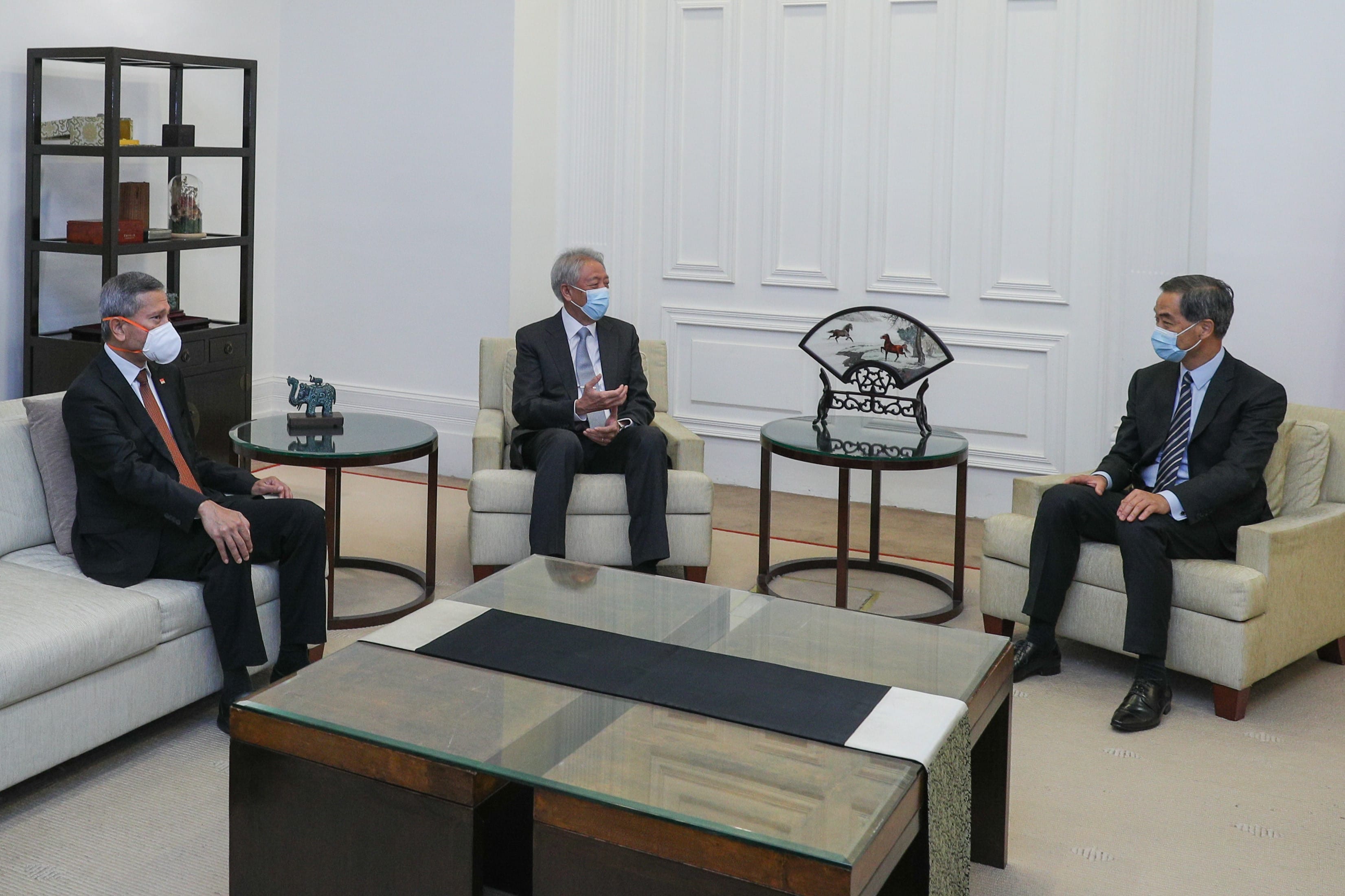 People at a meeting table with Singapore, Austria, and EU flags behind them.